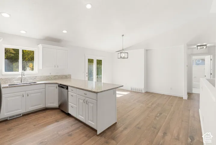 Kitchen featuring white cabinetry, light-toned countertops, stainless steel appliances, and wood-finish flooring