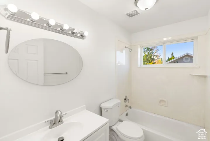 Bathroom featuring a white vanity with an integrated sink, brushed nickel faucet, and an oval mirror