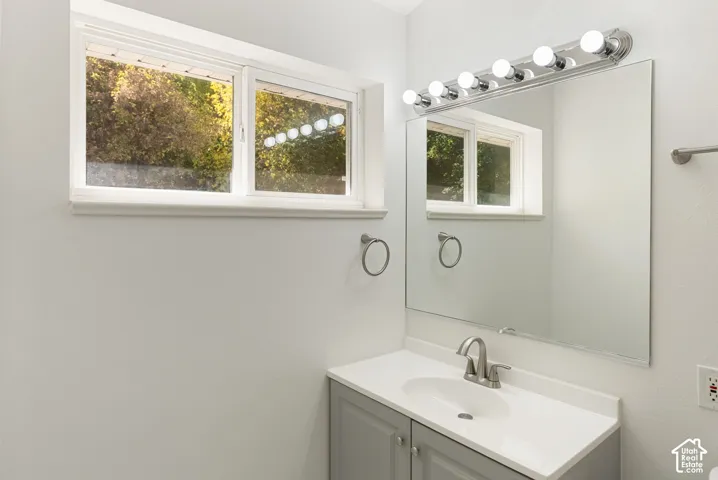 White vanity with a single basin sink, brushed nickel faucet, and a large mirror