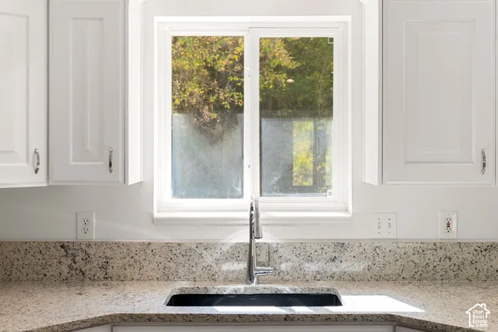 White shaker cabinetry, light-toned speckled countertop, undermount sink, chrome gooseneck faucet, and white framed window