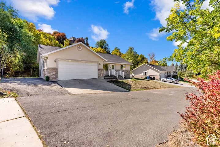 Exterior featuring a two-car garage, stone veneer accents, and a paved driveway