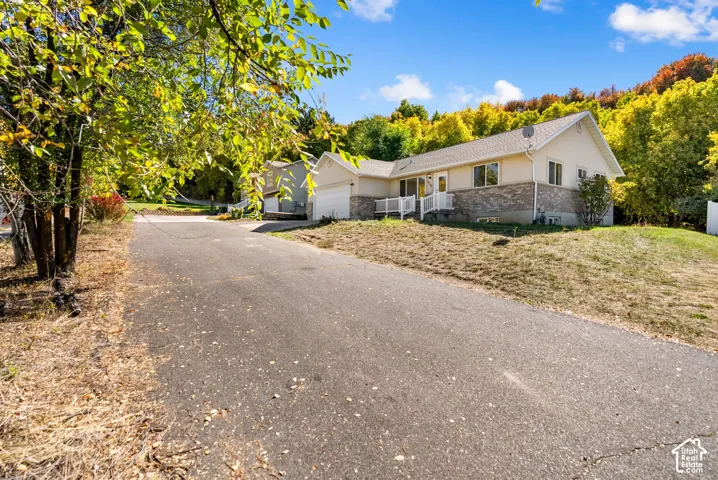 Paved driveway leading to a residence with a light-colored siding and a partial brick facade