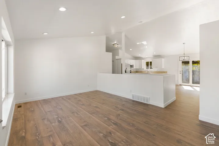 Spacious interior featuring wood-finish flooring, recessed lighting, and vaulted ceilings