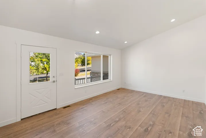 Wood-finish flooring, recessed lighting, vaulted ceilings, and a glass-paneled door