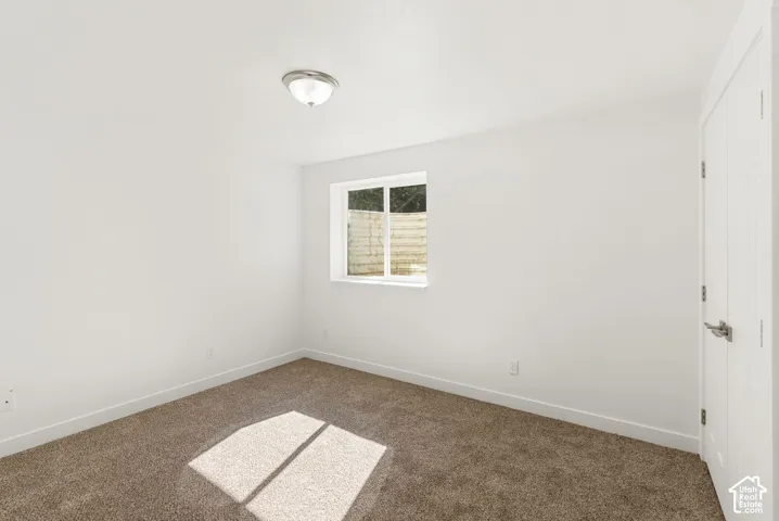 Neutral wall color with a window, wall-to-wall carpeting, and a flush mount light fixture