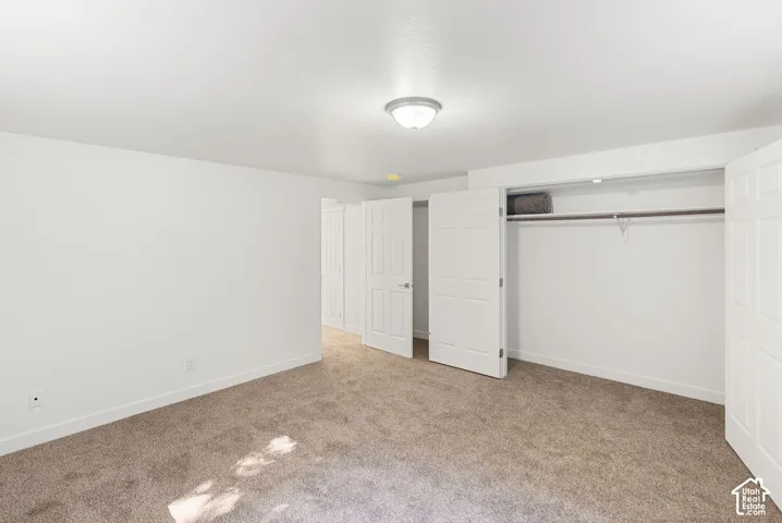 Neutral tone wall paint, flush mount ceiling light fixture, carpeted flooring, and a built-in closet with bi-fold doors