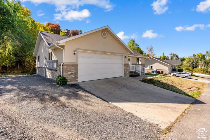 Exterior featuring a two-car garage, partial brick facade, stucco siding, and a concrete driveway