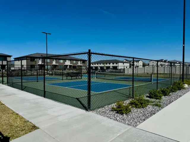 Fenced pickleball courts with hardscaping and landscaped rock beds