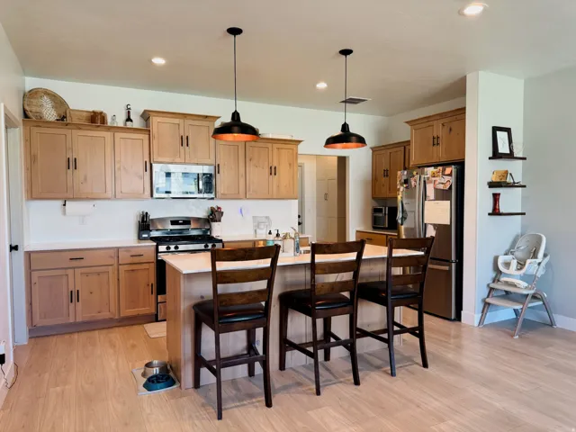 Kitchen featuring wood-finish flooring, recessed lighting, wood cabinetry, a center island, and stainless steel appliances