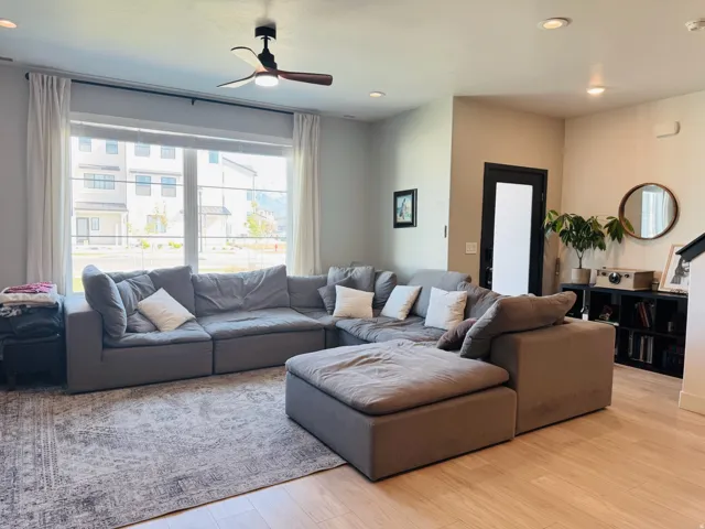 Recessed lighting and a ceiling fan illuminate this living space, featuring wood-finish flooring