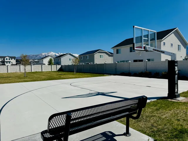 Outdoor basketball court with painted lines, integrated backboard, and a surrounding grass area
