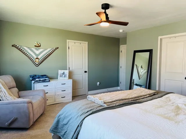 Carpeted bedroom featuring a contemporary ceiling fan, solid interior doors, and a neutral wall color