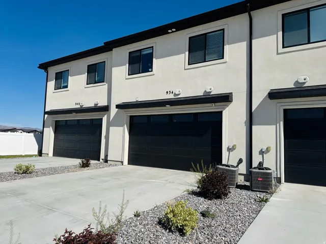 Two-story stucco exterior with black-framed windows, black garage doors, and concrete driveways