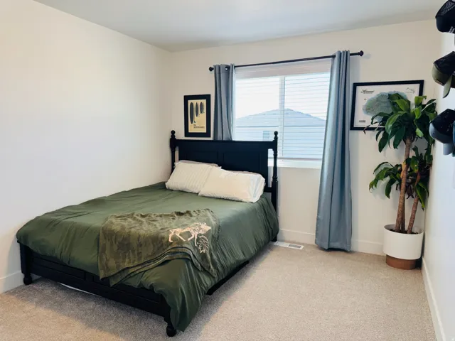 Recessed window with blinds and curtain rod, neutral wall color, light-colored carpeting, and white baseboards
