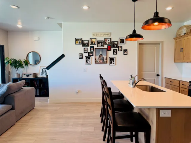 Open-concept living space featuring wood-finish flooring, recessed lighting, and a kitchen island with integrated sink