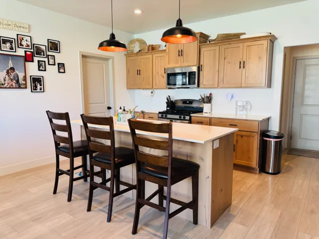 Kitchen featuring a center island, light wood-finish cabinetry, stainless steel appliances, and pendant lighting