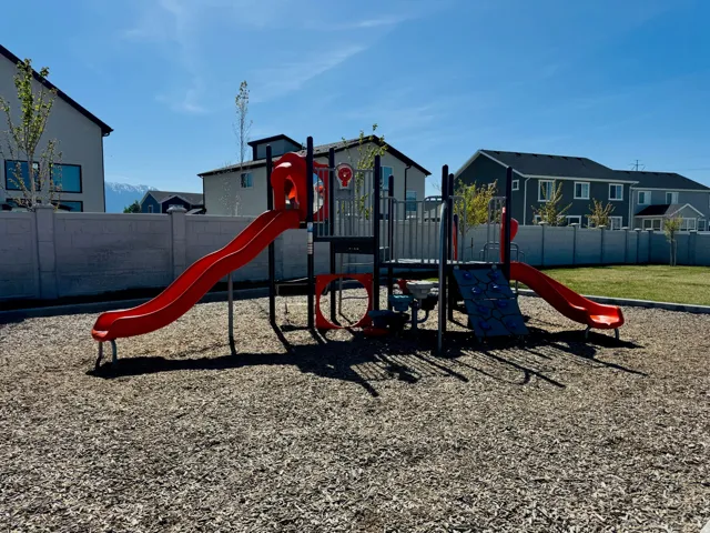 Playground area featuring two red slides, a climbing wall, and a wood chip ground cover
