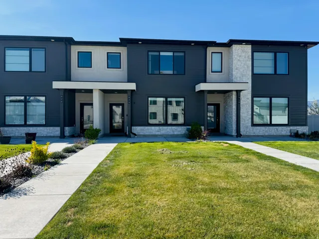 Modern façade with dark horizontal siding, light-toned stone accents, and expansive dark-trimmed windows