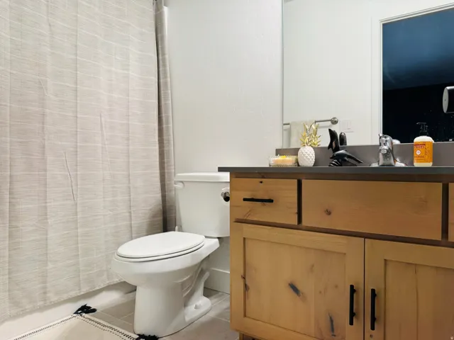 Wood-finish vanity with dark hardware, a rectangular sink, and a large mirror