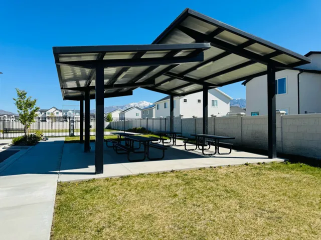 Covered outdoor seating area featuring multiple picnic tables and a concrete pad