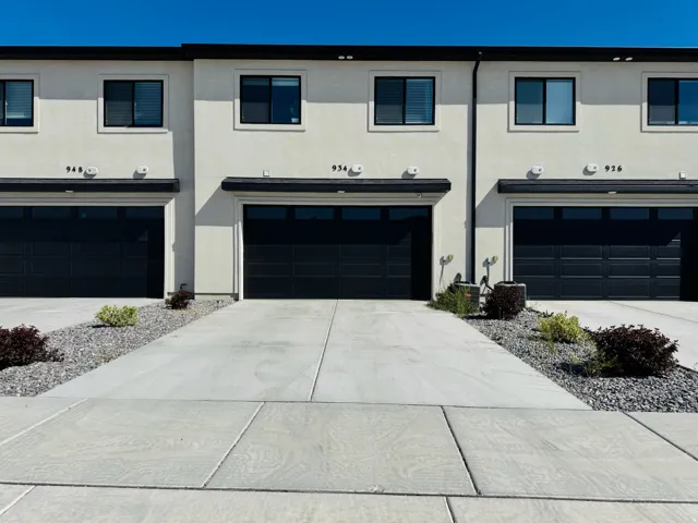 Contemporary stucco exterior with dark-framed windows, black garage doors, and concrete driveways