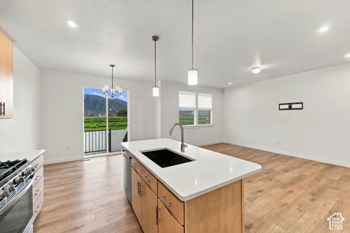 Open-concept living space featuring wood-finish flooring, recessed lighting, a kitchen island with an integrated sink, white countertops, and a sliding glass door