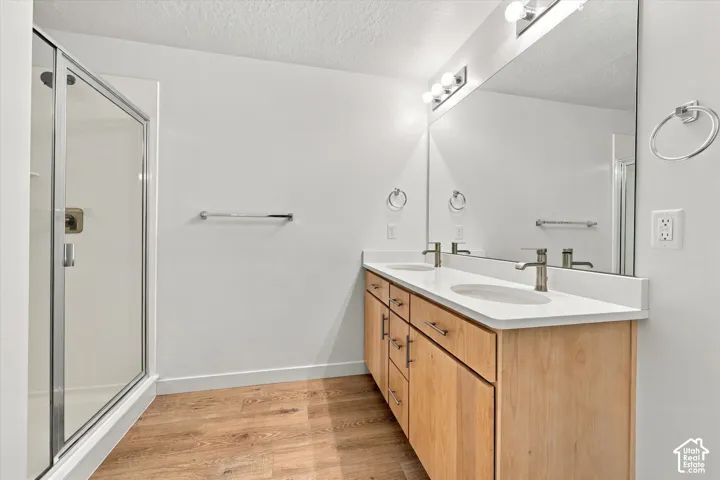 Double vanity with light wood-finish cabinetry, white countertop, and brushed nickel fixtures