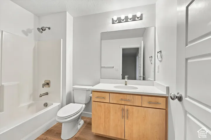Bathroom featuring a light wood-finish vanity, white countertop, integrated sink, and brushed nickel fixtures