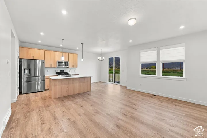 Open-concept living area featuring wood-finish flooring, recessed lighting, and a kitchen island with pendant lighting