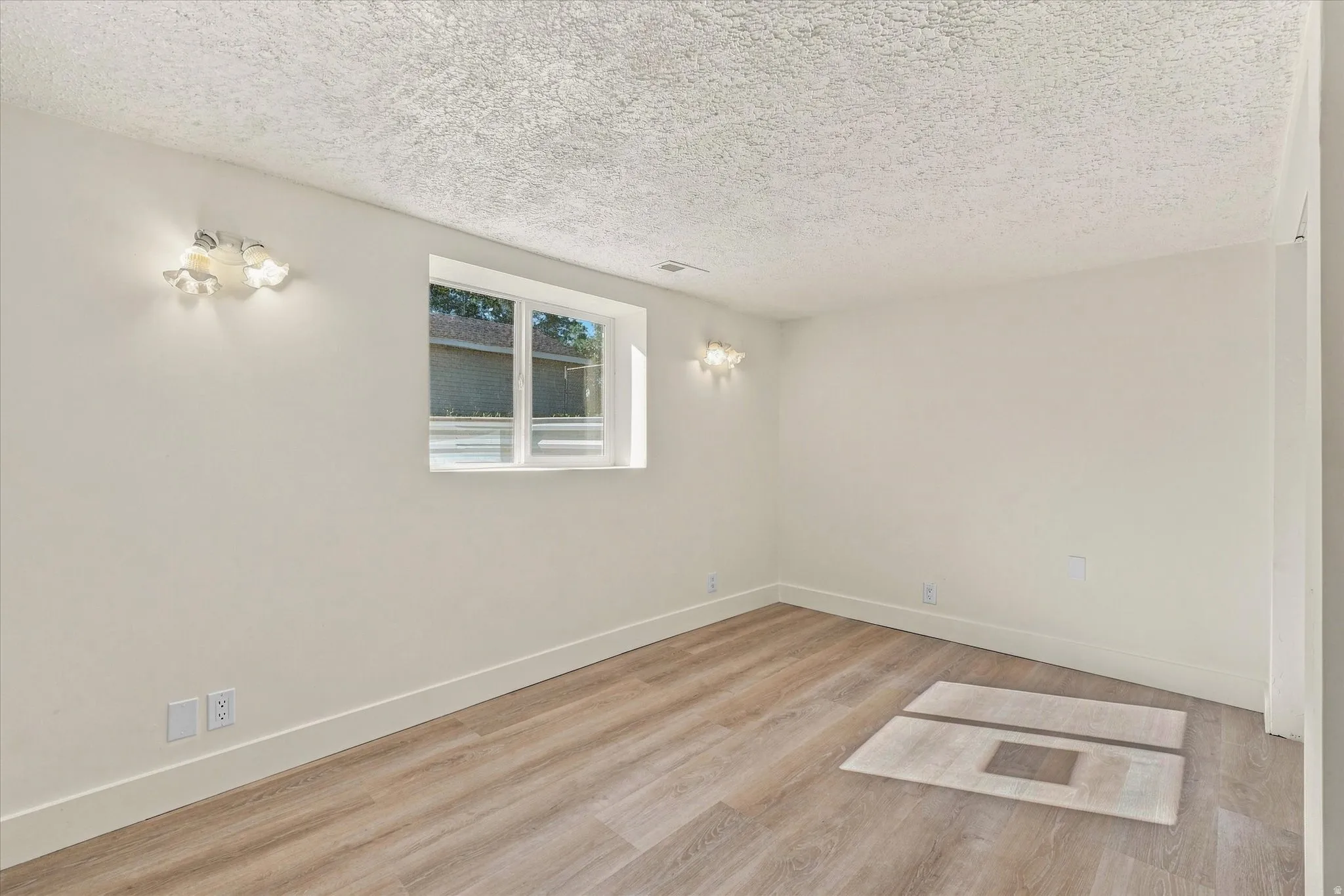 Recessed window with white trim, wood-finish flooring, white baseboards, and wall-mounted light fixtures