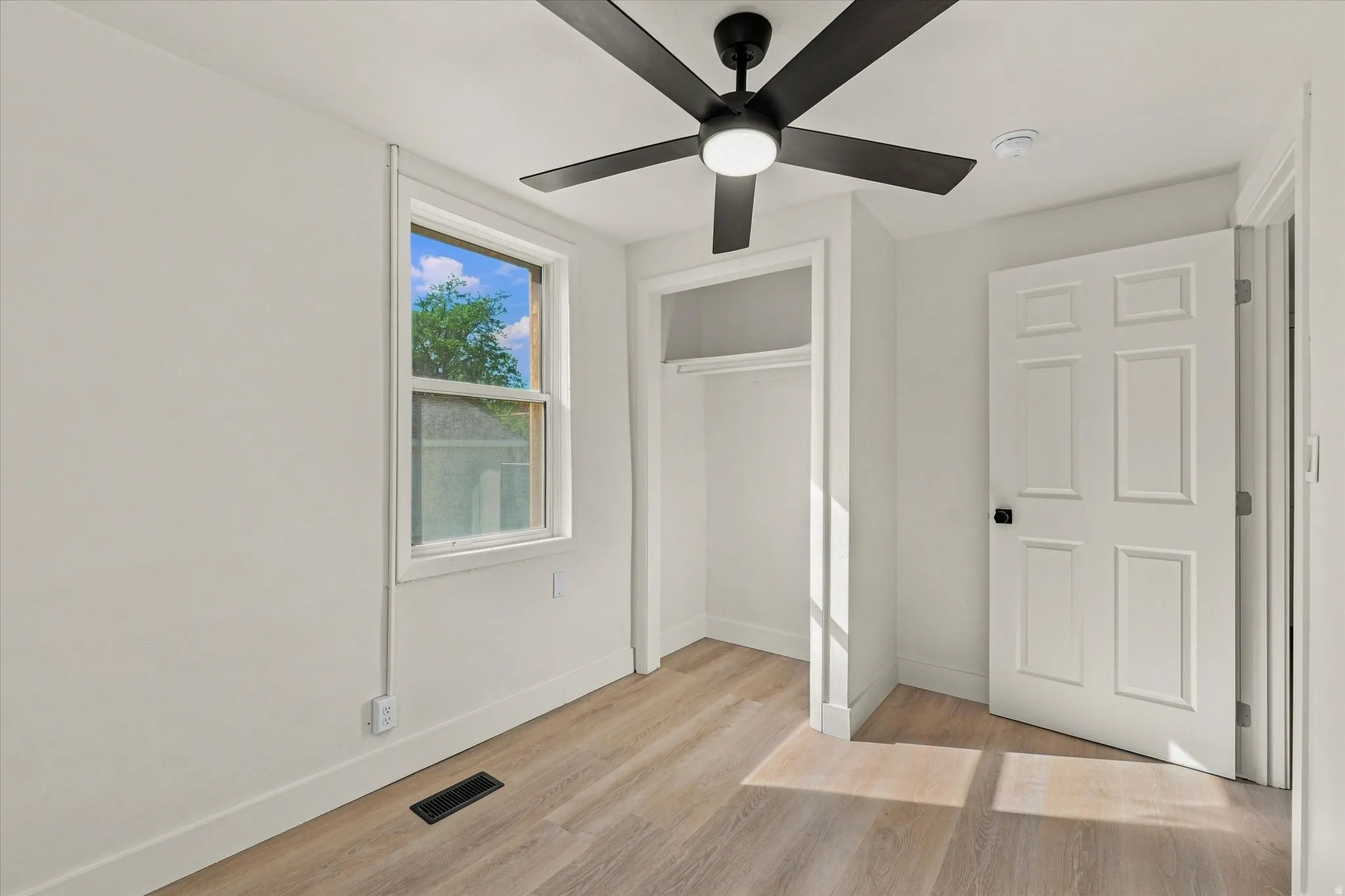 Wood-finish flooring, white walls, and a window with white trim