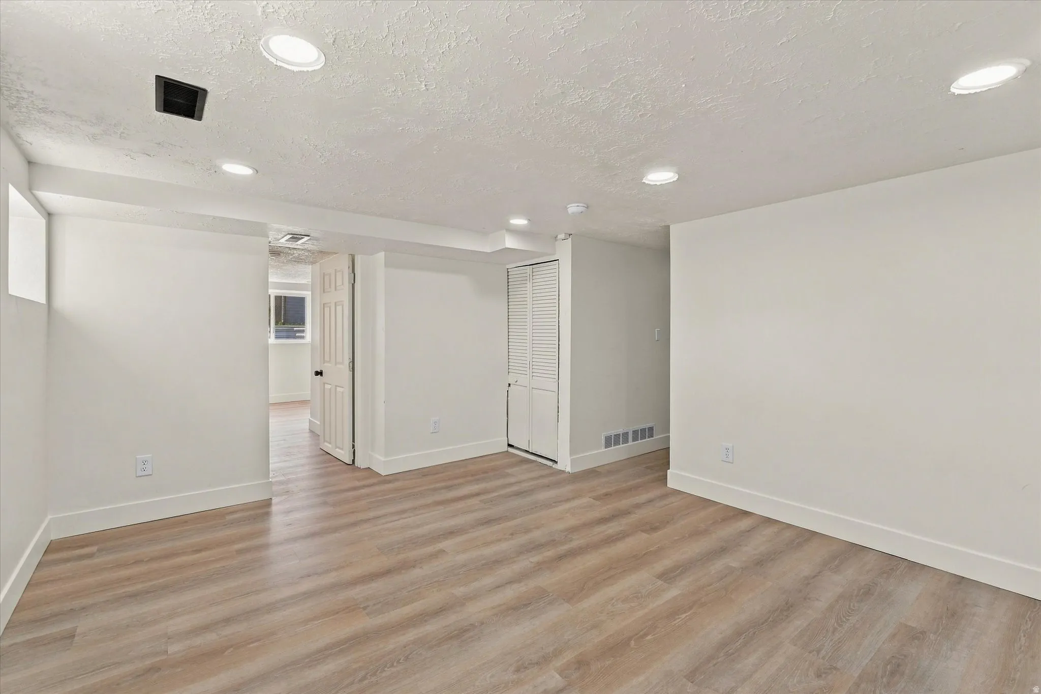 Wood-finish flooring, recessed lighting, white walls, and white trim