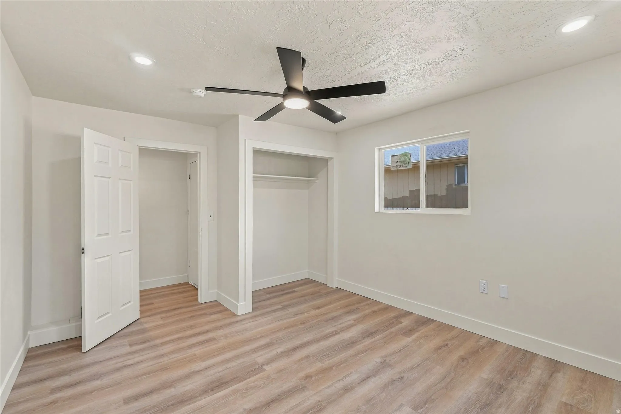 Neutral wall paint, wood-finish flooring, recessed lighting, ceiling fan, and a window