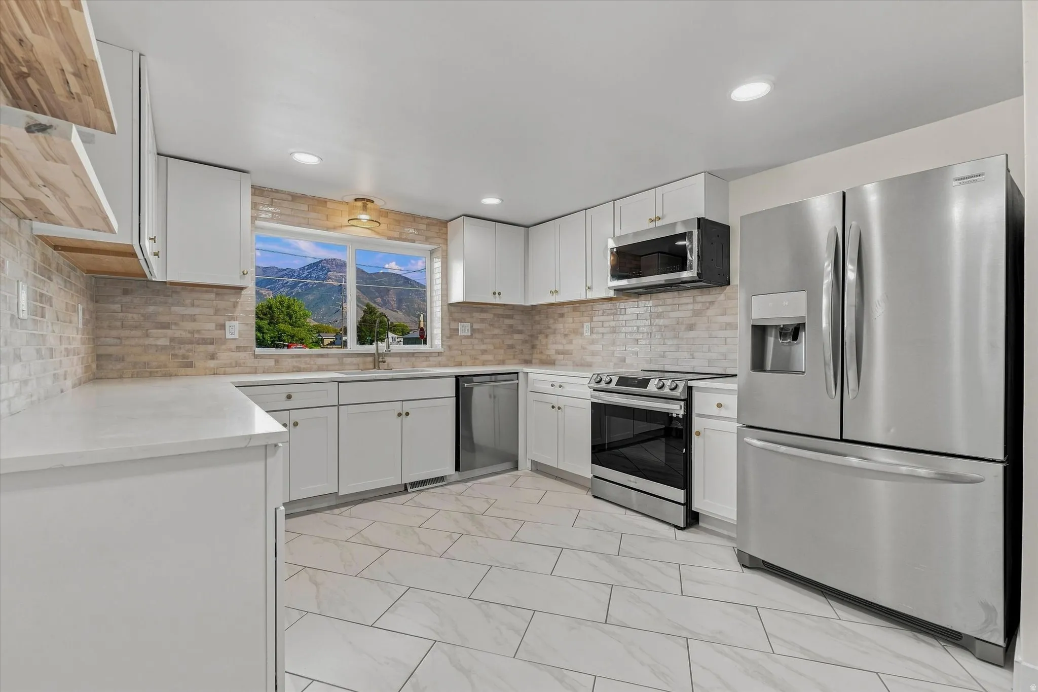 Kitchen featuring white cabinetry, stainless steel appliances, a tile backsplash, light-toned countertops, and large format floor tiling