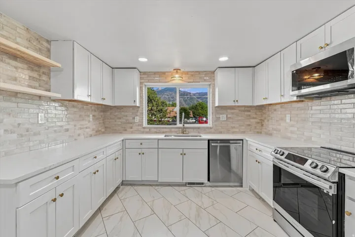 Kitchen featuring white cabinetry, light countertops, a tile backsplash, stainless steel appliances, and wood-finish flooring