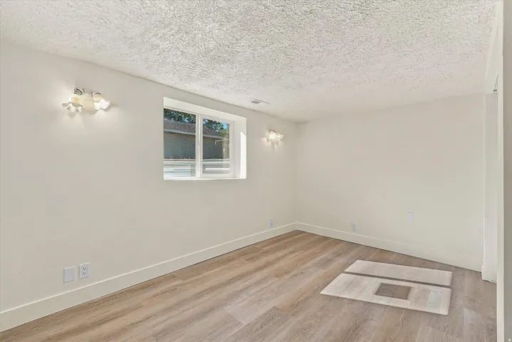 Recessed window with white trim, wood-finish flooring, white baseboards, and wall-mounted light fixtures