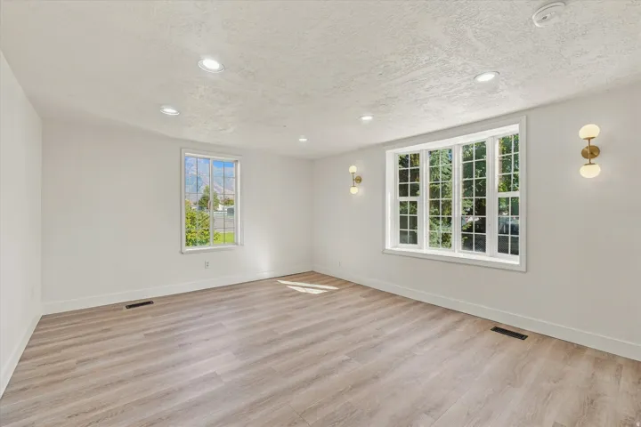Expansive room featuring wood-finish flooring, recessed lighting, and a large bay window