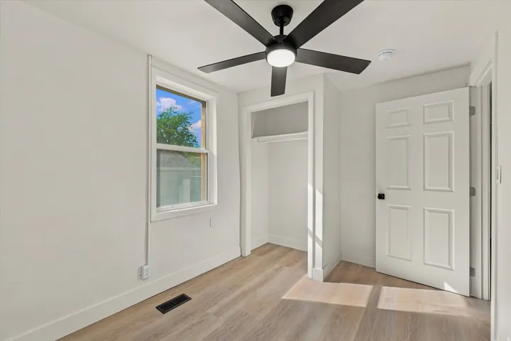 Wood-finish flooring, white walls, and a window with white trim