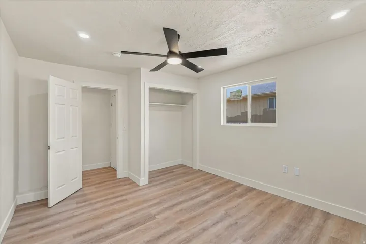 Neutral wall paint, wood-finish flooring, recessed lighting, ceiling fan, and a window