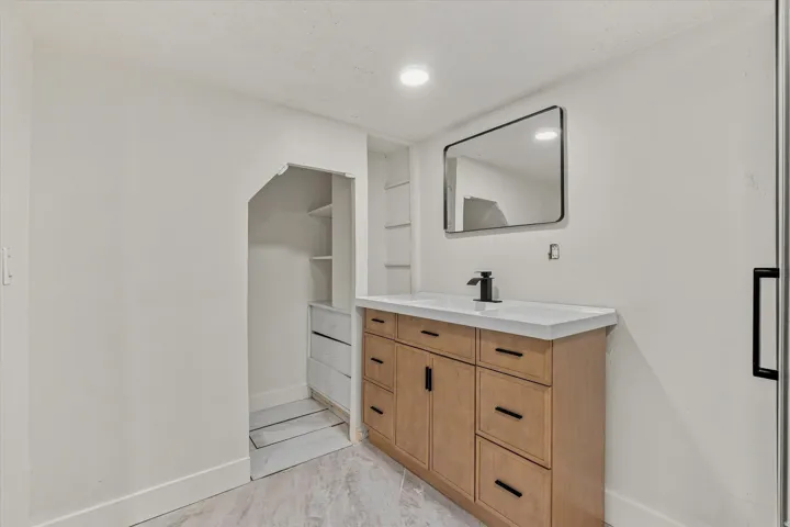 Wood-finish vanity with a white countertop and rectangular undermount sink