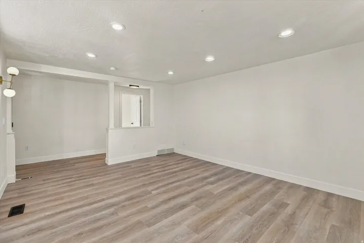 Spacious interior with wood-finish flooring, recessed lighting, and a modern wall-mounted fixture