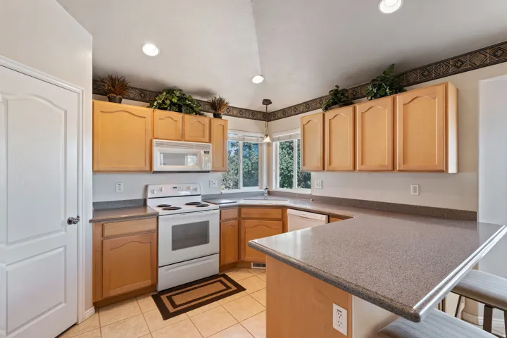 Kitchen. Tile floors. Vaulted Ceilings. Large windows. White appliances. Pantry.