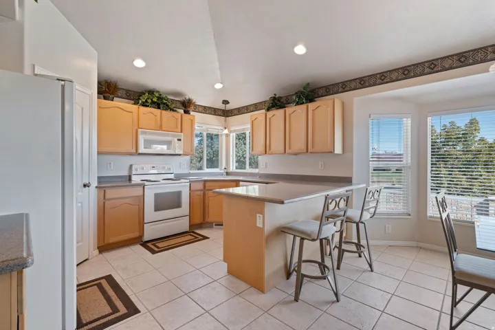 Kitchen. Tile floors. Vaulted Ceilings. Large windows. White appliances. Pantry.