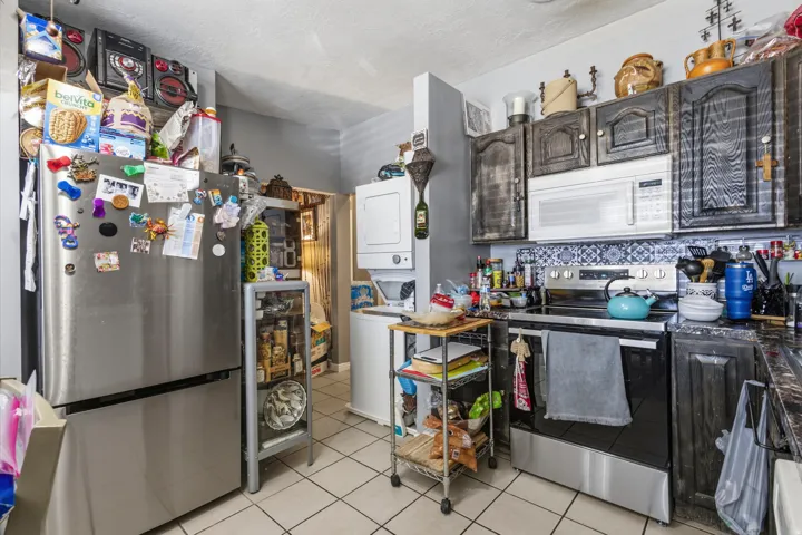 Stainless steel refrigerator, stainless steel range, built-in microwave, dark wood-finish cabinetry, and tile flooring