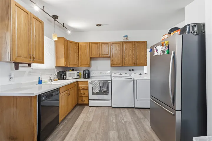 Kitchen featuring wood cabinetry, white countertops, a stainless steel refrigerator, and wood-finish flooring