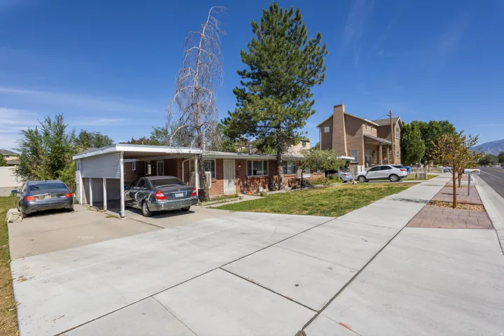 Brick exterior residence with an attached carport, concrete driveway, and front lawn