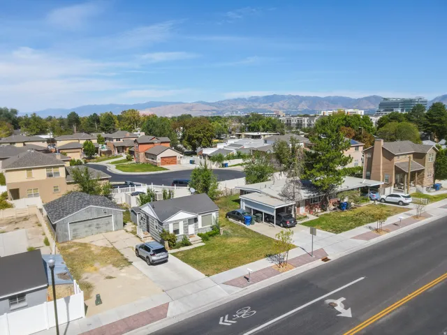 Aerial perspective showcasing varied residential architecture, established neighborhood setting, visible mountains, and urban infrastructure in the distance