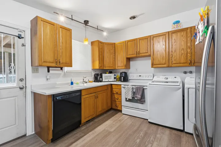 Kitchen featuring wood cabinetry, white countertops, built-in dishwasher, and wood-finish flooring
