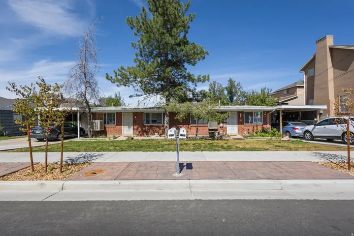 Red brick exterior with white trim, two covered carports, and a concrete sidewalk