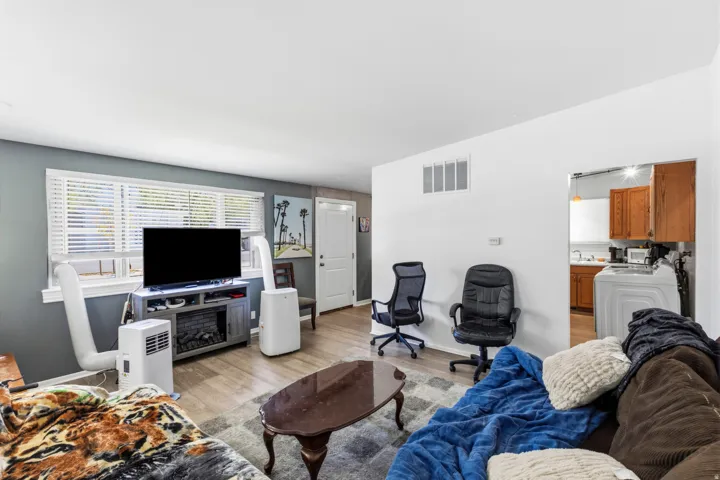 Wood-finish flooring throughout, white interior doors, and a window with white blinds